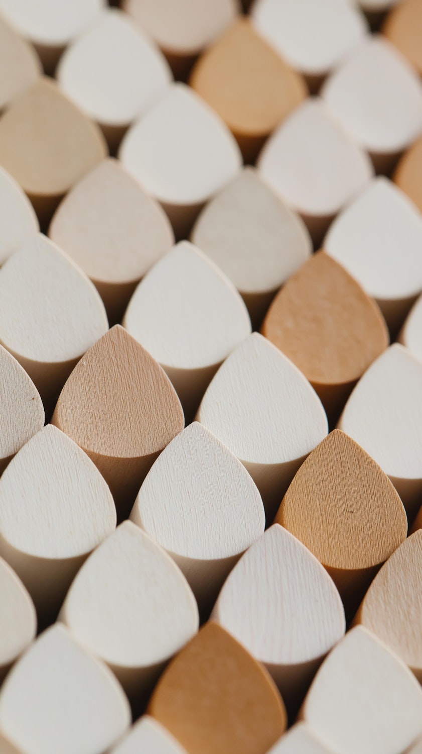 Interlocking teardrop-shaped wooden blocks in beige and tan, arranged into a symmetrical repeating pattern.